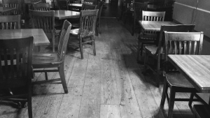 schwarz weiß Bild von altem Gastraum, Stühle und Tische, Holzboden