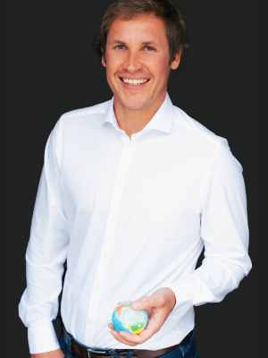 Philipp mit weißem Hemd vor schwarzem Hintergrund, lächelnd.